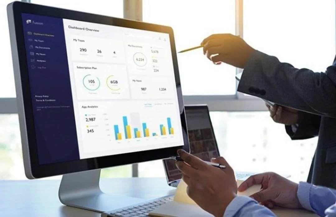 Team discussing a business dashboard on a monitor