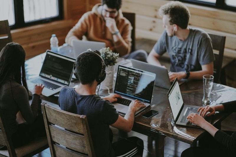 A small startup team working on laptops around a table